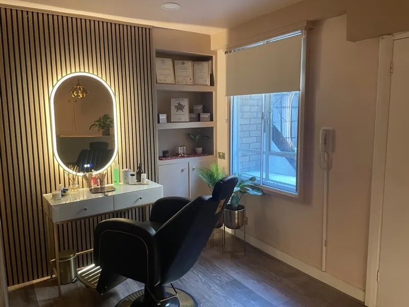 Studio room with a backlit mirror, slatted wall, styling chair and framed certificates